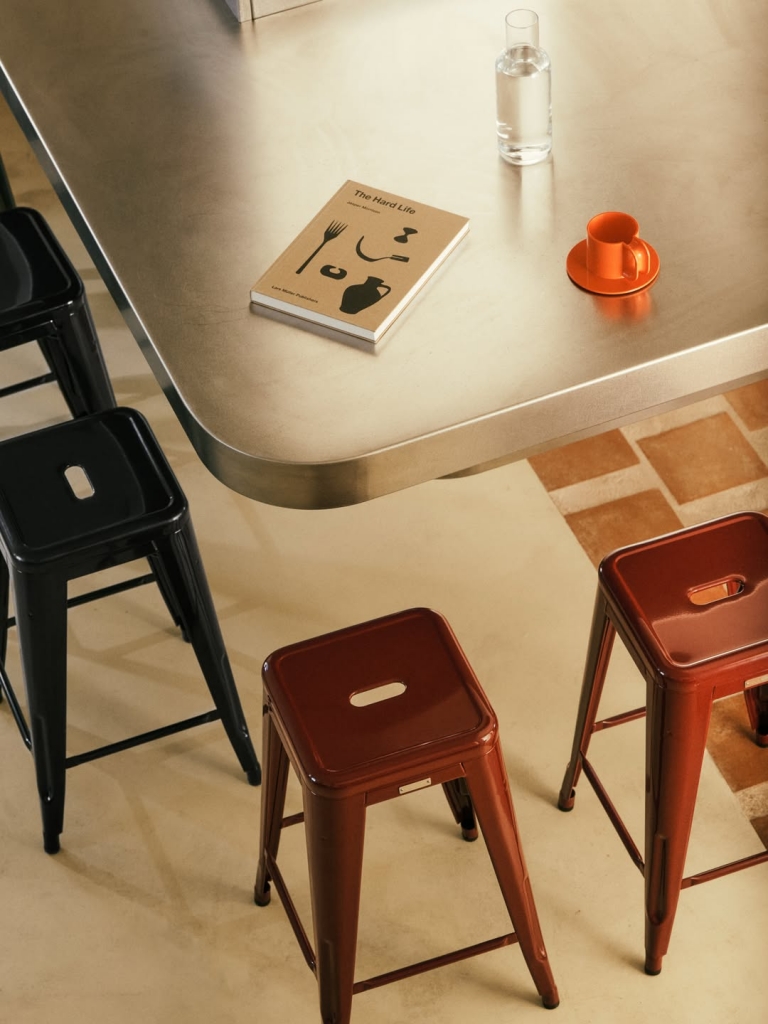 ICFF contemporary metal table with earthy red and black stools