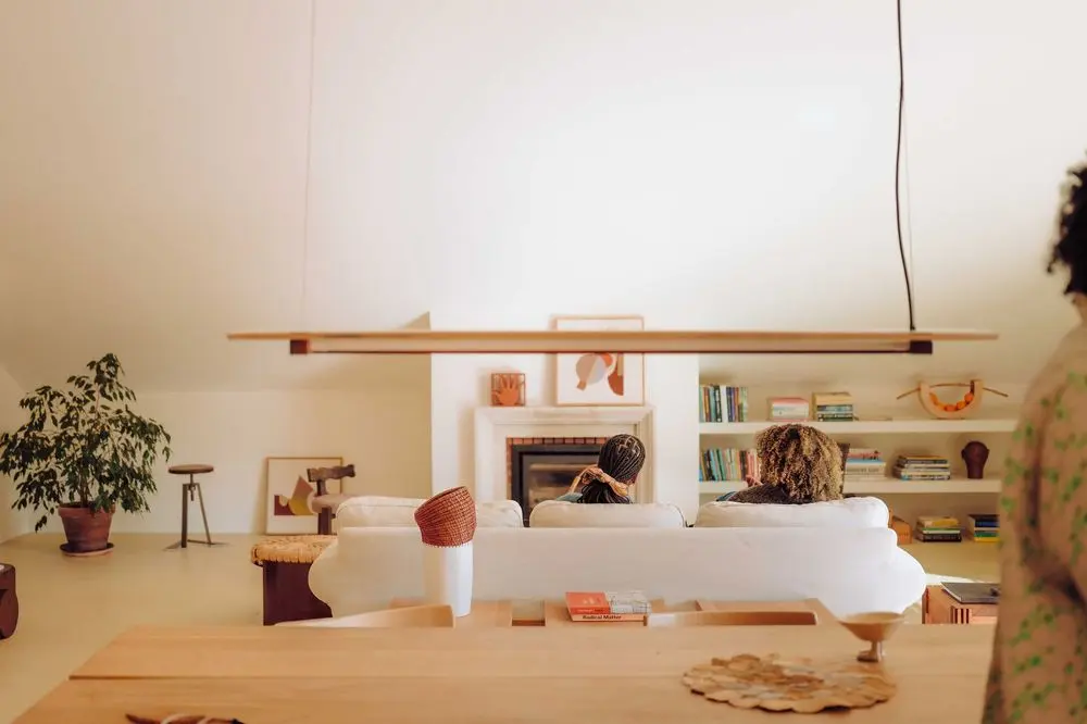 white walls, white sofa, fireplace, white bookcase, wood dining table, suspension light, plant, lisbon design week