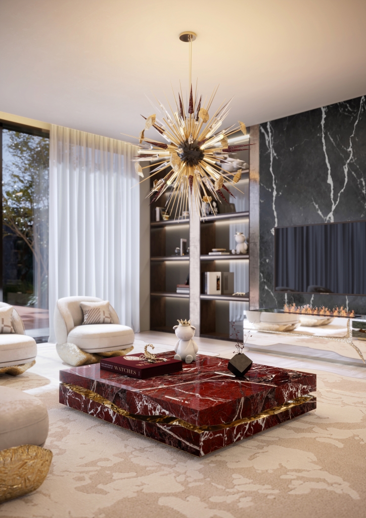 Modern living room with dramatic gold sunburst crystal chandelier with red accents, square red marble coffee table with gold inlay, ivory boucle armchairs with gold sculptural bases, dark veined marble fireplace wall, and built-in bookshelf living rooms