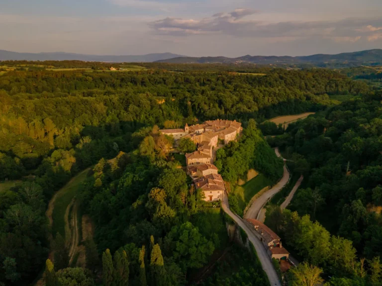 ols money style, Historic Tuscan estate featuring restored stone buildings, vineyards, olive groves, and rolling countryside views.