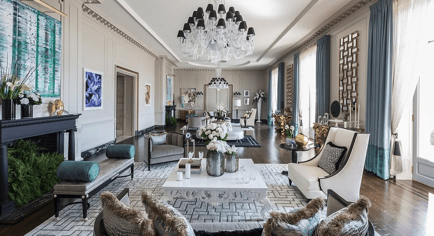 Spacious and aristocratic living room in a classic style, decorated with a luxurious dark fireplace, elegant sofas and armchairs arranged on a geometric rug, stately blue curtains on the windows, and a magnificent chandelier of black and translucent crystal hanging from the detailed ceiling, interior designers