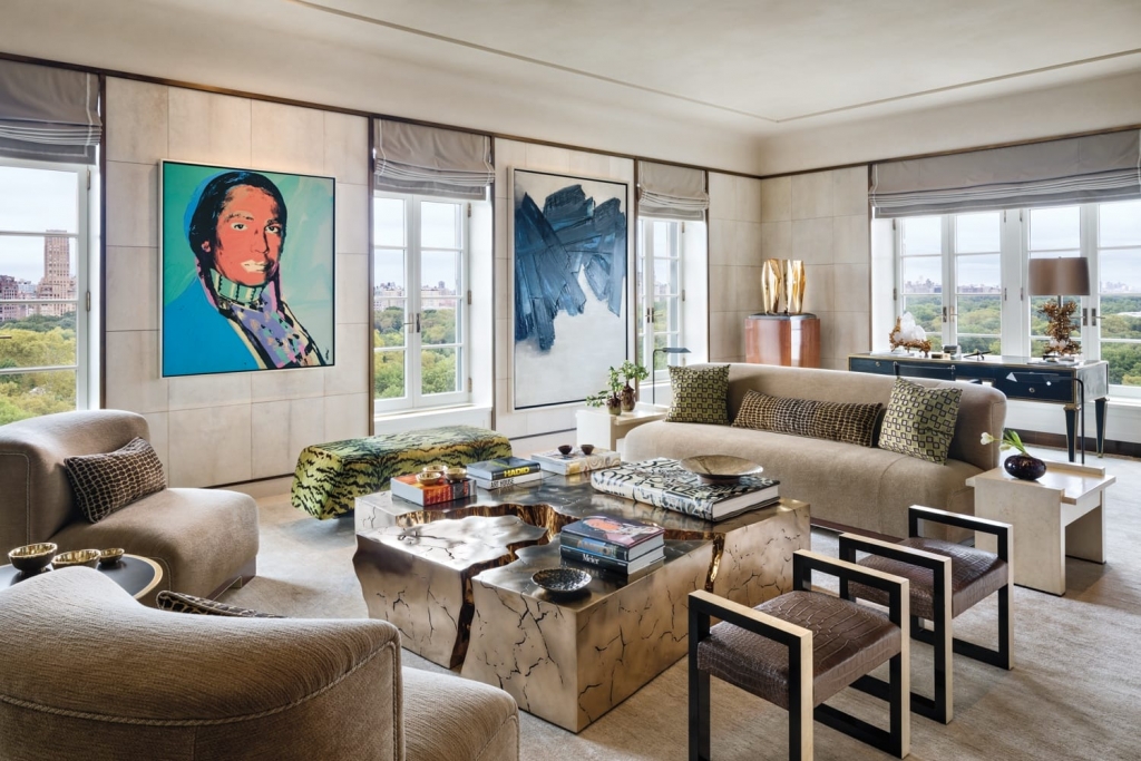A sophisticated penthouse living room overlooking Central Park, highlighting a metallic textured coffee table, a colorful portrait painting, and neutral-toned luxury seating, composed by interior designers
