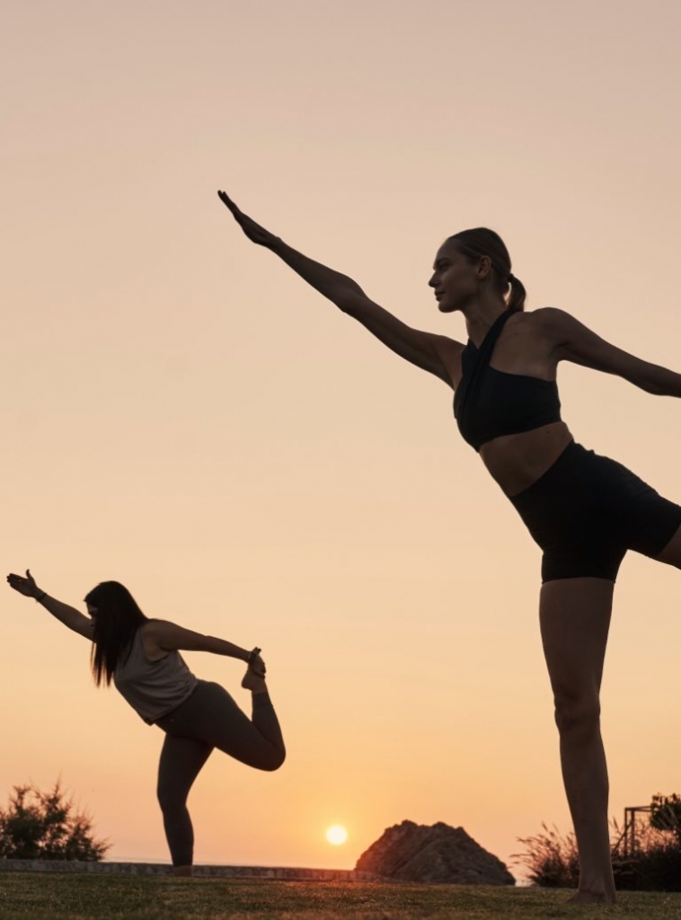 Two girls doing yoga during sunset time