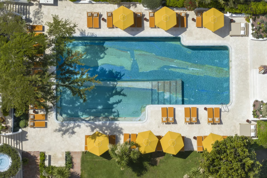 old money style, Aerial view of a rooftop pool with yellow umbrellas and a landscaped garden.