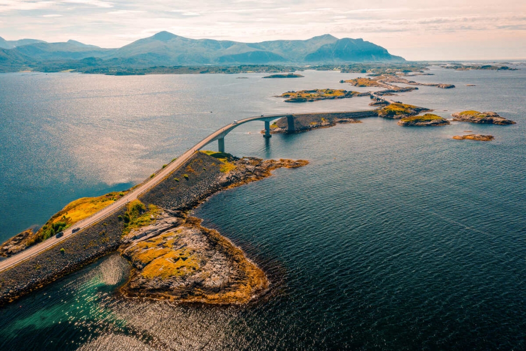 An aerial view of a winding bridge connecting small islands surrounded by deep blue water, Coastal Roads.