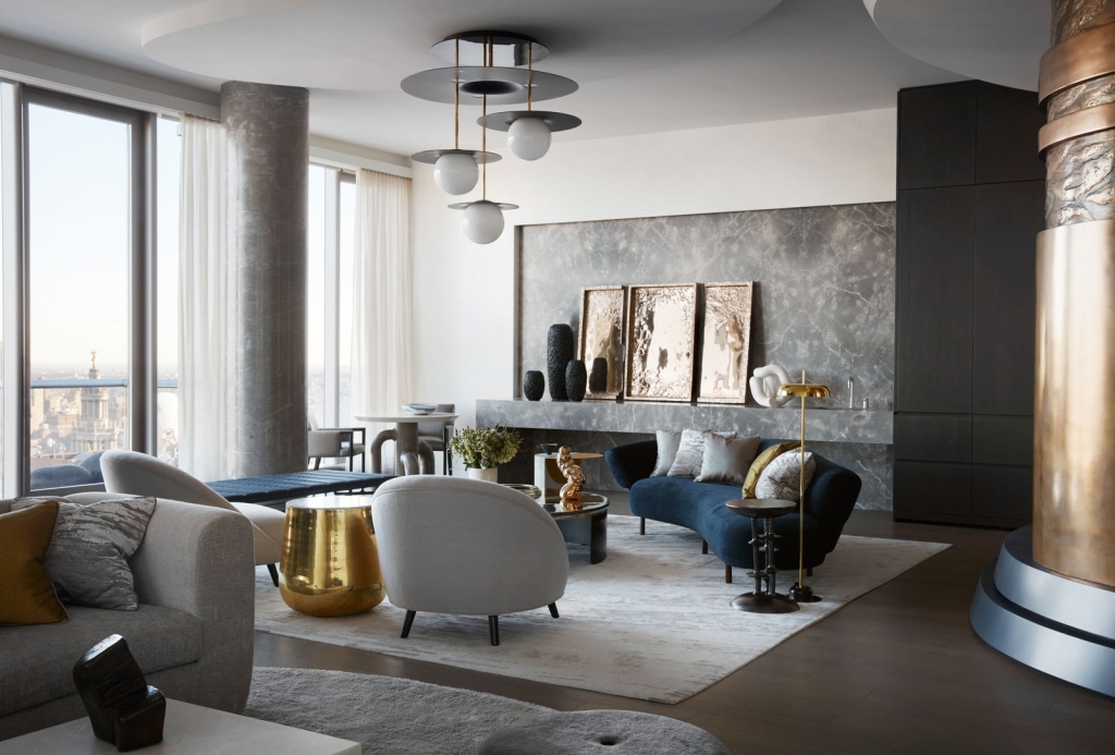 A high-rise apartment living room with sweeping city views, featuring curved modern furniture in blue and white, metallic gold accents, and a marble wall statement, structured by interior designers