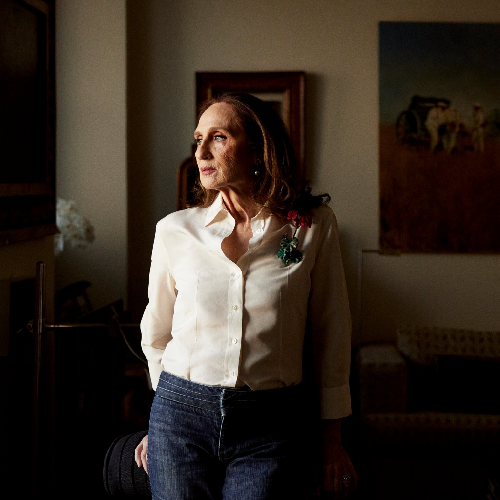 A close-up portrait of a woman with short dark hair, wearing a white shirt and looking directly at the camera in a warmly lit setting at PAD Saint-Tropez 2026.