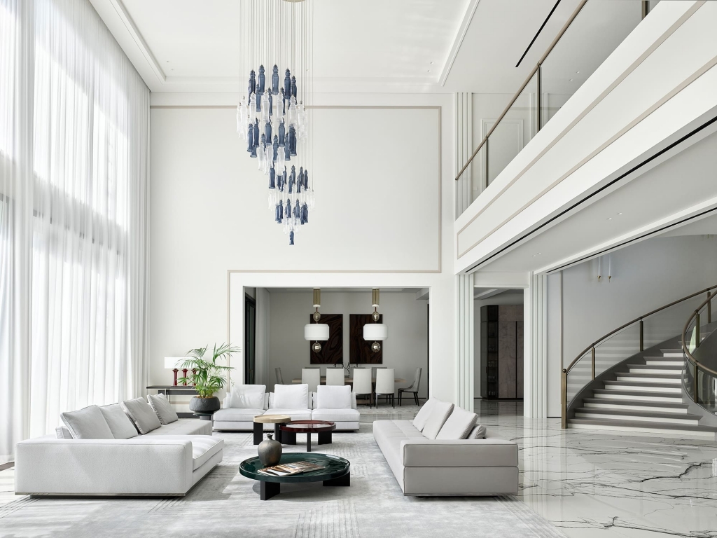 Modern lobby lounge with checkerboard stone flooring, marble-clad columns, dome pendant lights, walnut shelving displaying books and cycling memorabilia, and black bistro chairs. interior designers