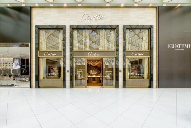 Fachada da loja Cartier em tons dourados e bege, com vitrines geométricas e piso de mármore claro em shopping de luxo - lojas de luxo em São Paulo