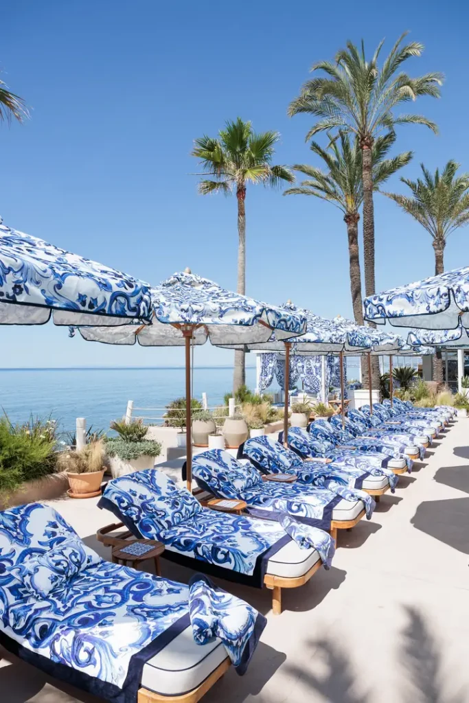 Relaxed luxury with rows of Dolce&Gabbana sun loungers dressed in blue-and-white Blu Mediterraneo fabrics overlooking the Mediterranean coastline in Marbella.