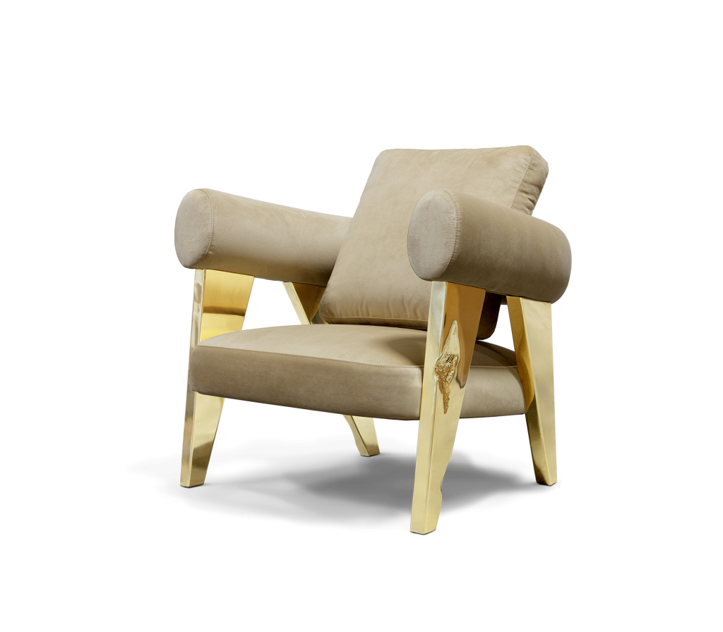 Beige velvet accent chair with cylindrical bolster arms and angular gold legs featuring a sculptural gold accent detail- luxury armchair
