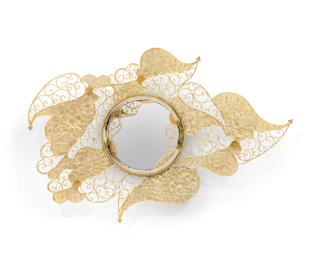 Close-up of a gold filigree wall mirror designed as intricate lace-like leaves encircling a round mirrored center, luxury design.