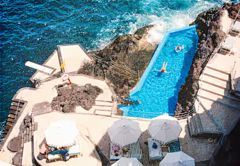 Portugal’s Bucket List Hotels — Reid's Palace, A Belmond Hotel, Madeira, a historic clifftop luxury hotel overlooking the Atlantic Ocean, with pastel façades, lush tropical gardens, and elegant colonial-era architecture.