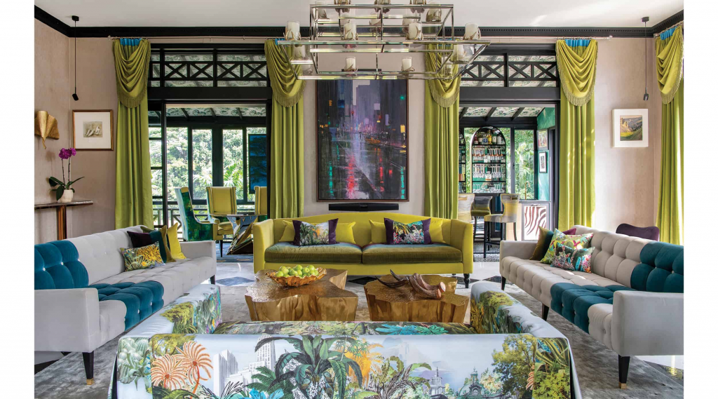 Nikki Hunt Interior Design, Maximalist tropical-style living room with a gold center table, white and blue sofas, a sofa with tropical patterned upholstery, and vibrant green curtains