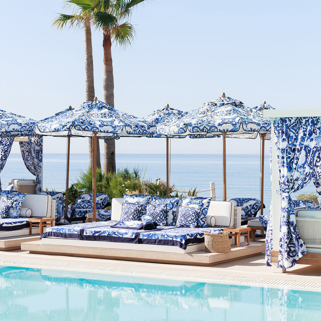 Relaxed luxury with rows of Dolce&Gabbana sun loungers dressed in blue-and-white Blu Mediterraneo fabrics overlooking the Mediterranean coastline in Marbella.