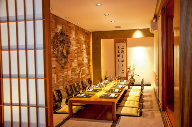 Sala privativa de estilo japonês com painel decorativo em madeira, caligrafia oriental na parede e mesa baixa com assentos no chão - melhores restaurantes em São Paulo