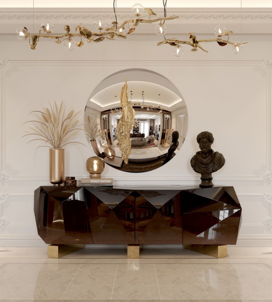 Convex round mirror above a bronze-toned geometric cabinet, with classical bust and golden branch pendant light overhead-luxury mirrors.