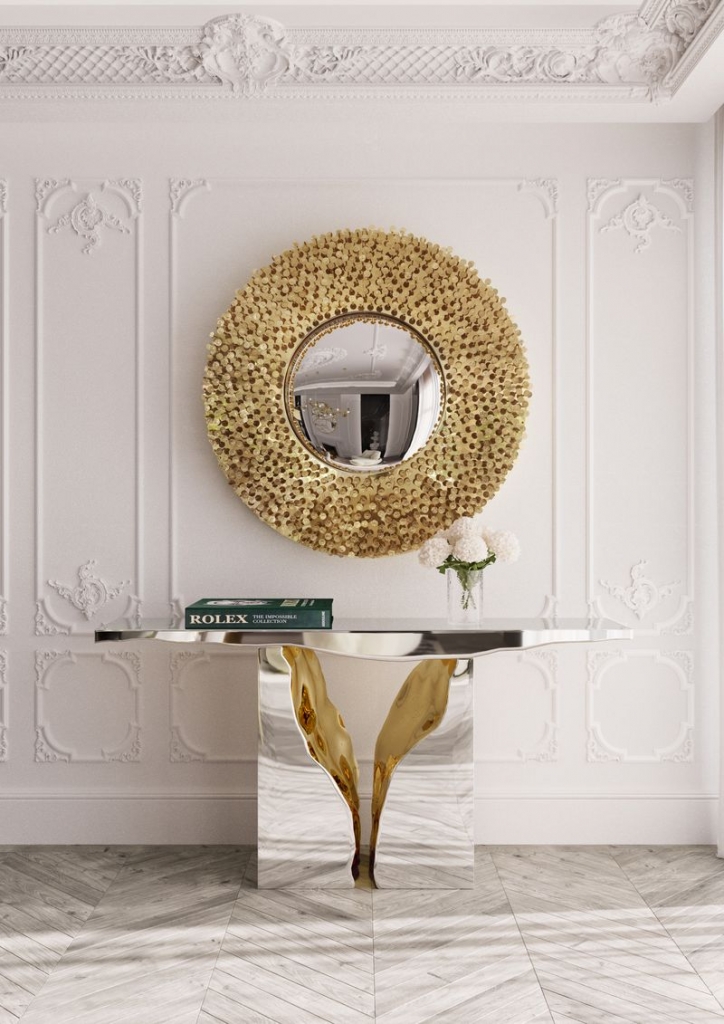 Round convex mirror with textured frame of layered gold discs, above a white marble console-luxury mirrors.