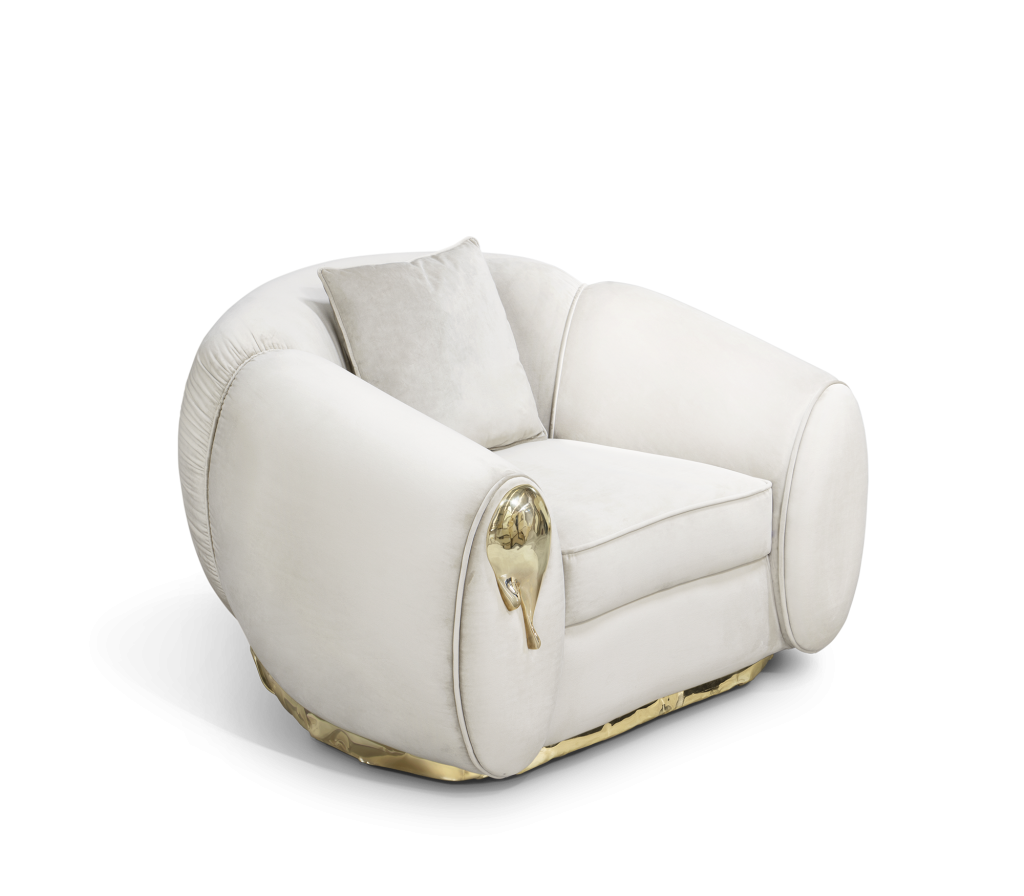Cream velvet armchair with rounded barrel-shaped arms and a sculptural gold droplet accent on the side panel-luxury armchair