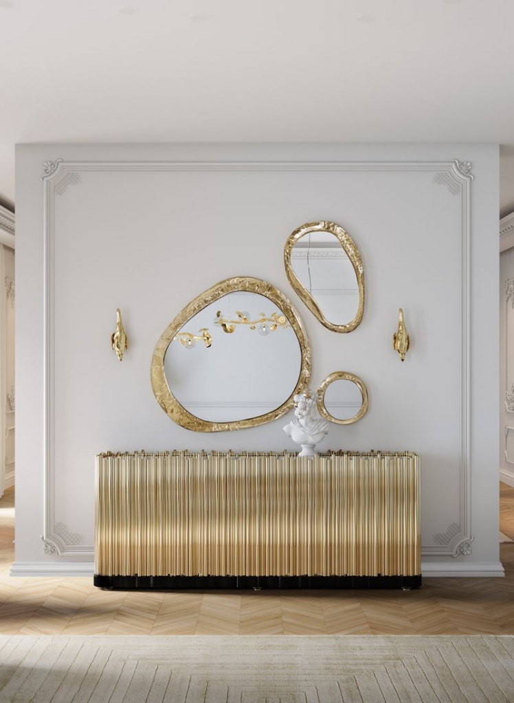 Set of three organic-shaped gold mirrors with hammered textured frames, displayed above a ribbed gold console table styled with a marble bust, luxury design.