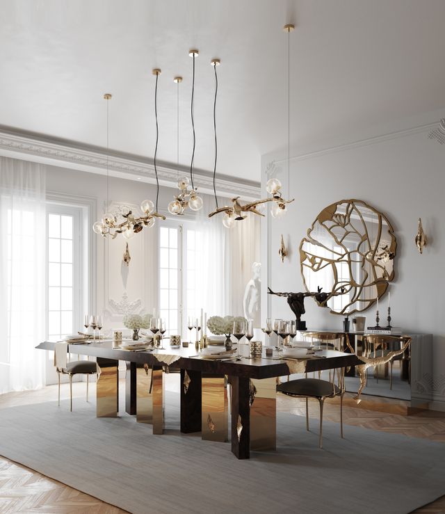 Elegant dining room with dark wood table on faceted gold legs beneath gold branch-style chandeliers -luxury dining table