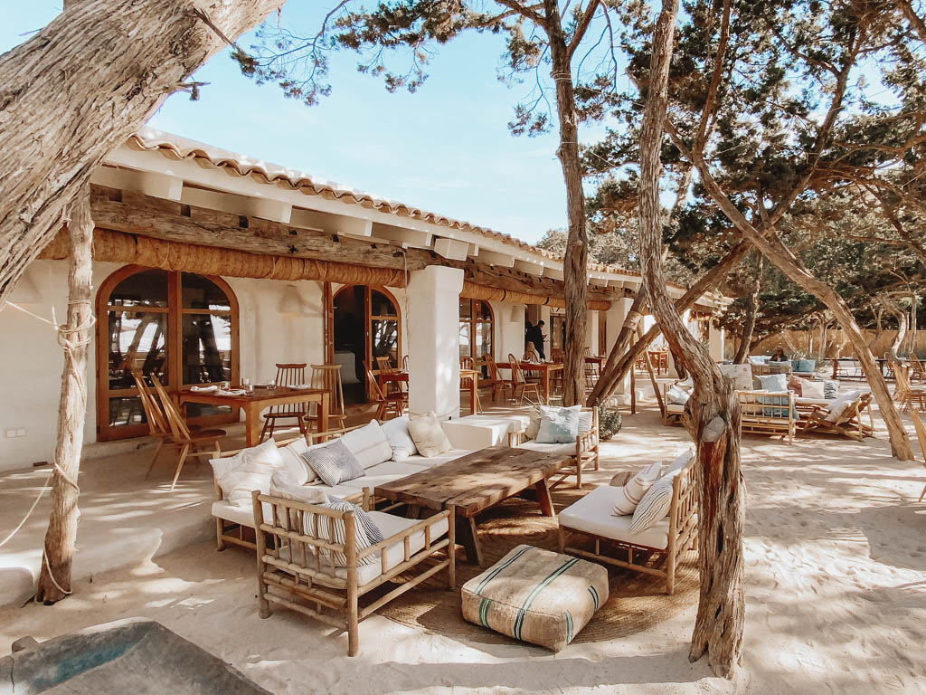 Beachfront restaurant with wooden pergola, set tables, and sand-side sofas -luxury beach clubs in Europe