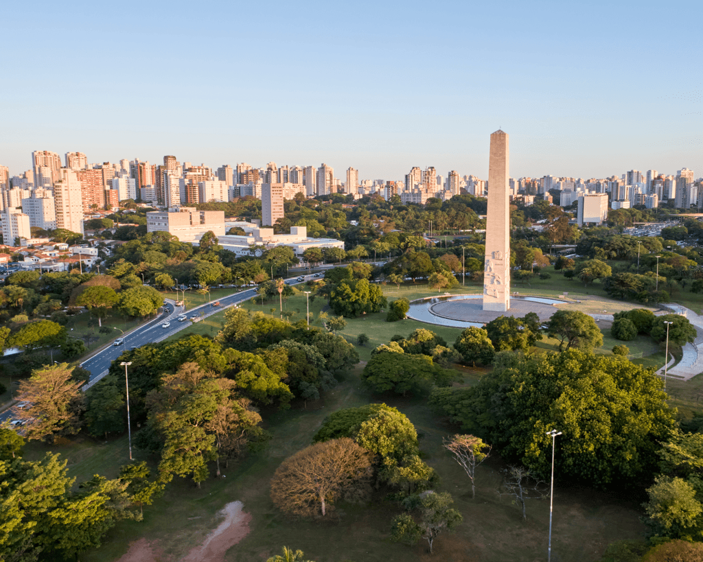 Aerial view of an obelisk in a lush green park, surrounded by trees and the city skyline -top places to live in São Paulo