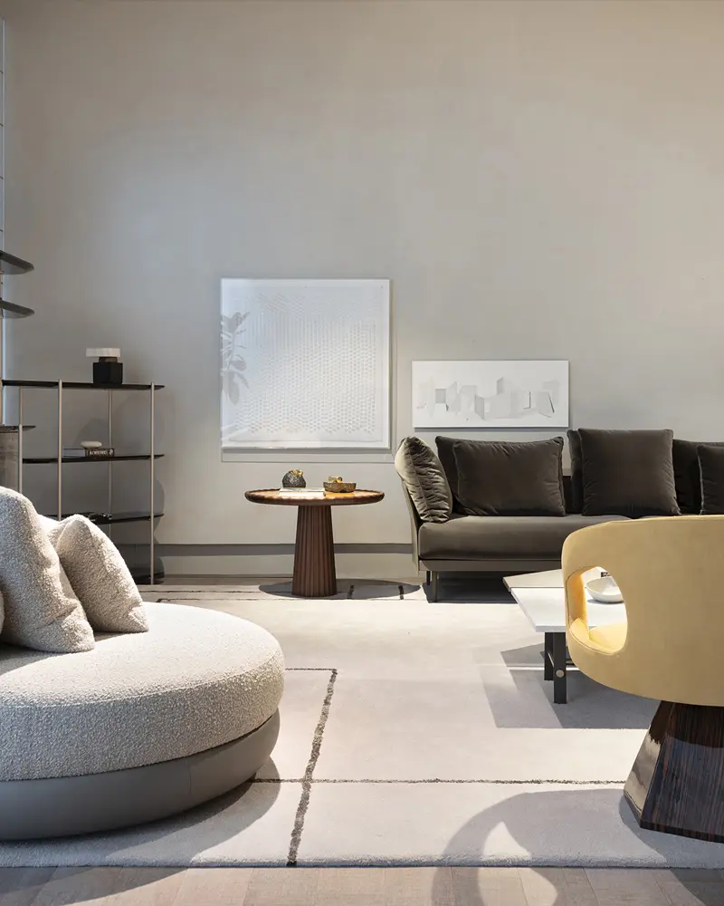 Neutral-toned living room vignette with a round bouclé ottoman, dark green sofa, and yellow curved chair -top showrooms in São Paulo