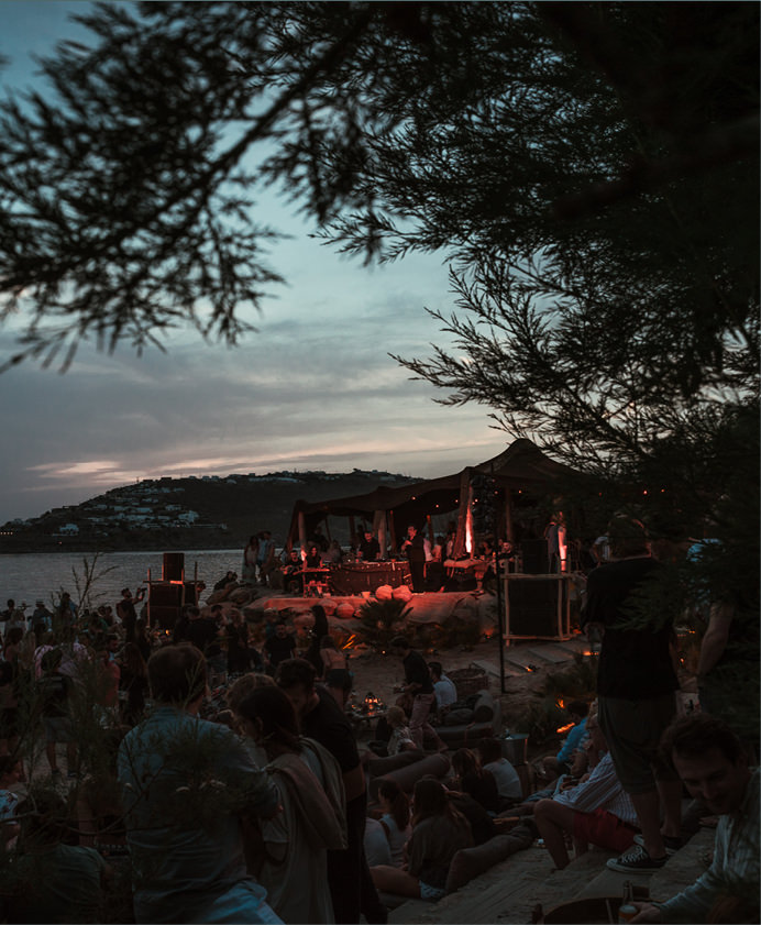 Sunset beach party with a crowd, illuminated tent, and lively atmosphere -luxury beach clubs in Europe