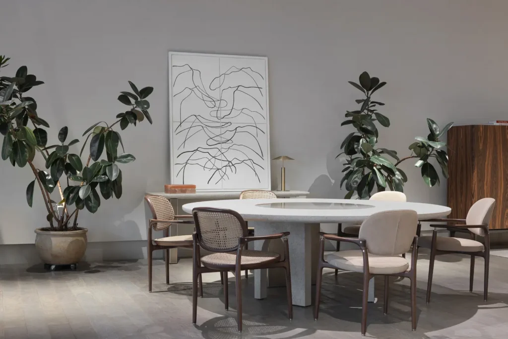 Round dining table set with cane-back and upholstered chairs beneath a large line-art painting -top showrooms in São Paulo