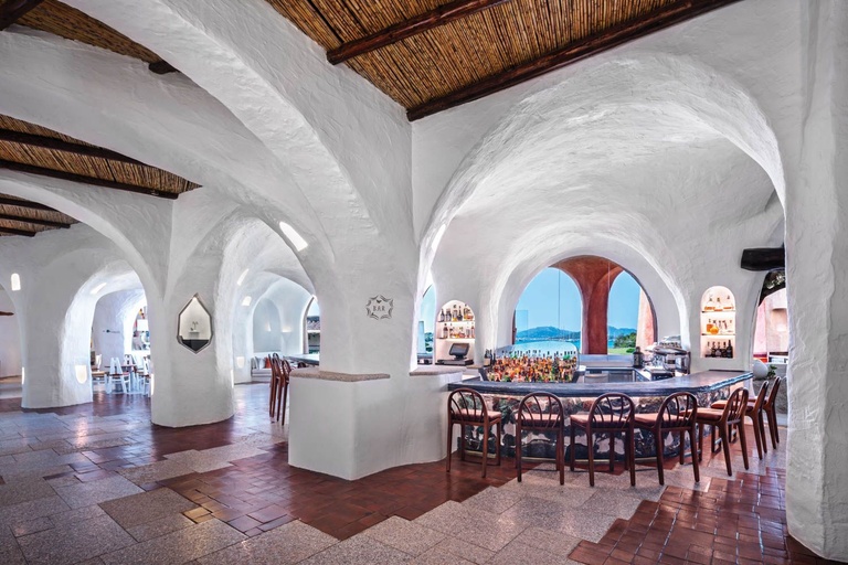 White vaulted stone interior with an arched bar area and terracotta floor tiles