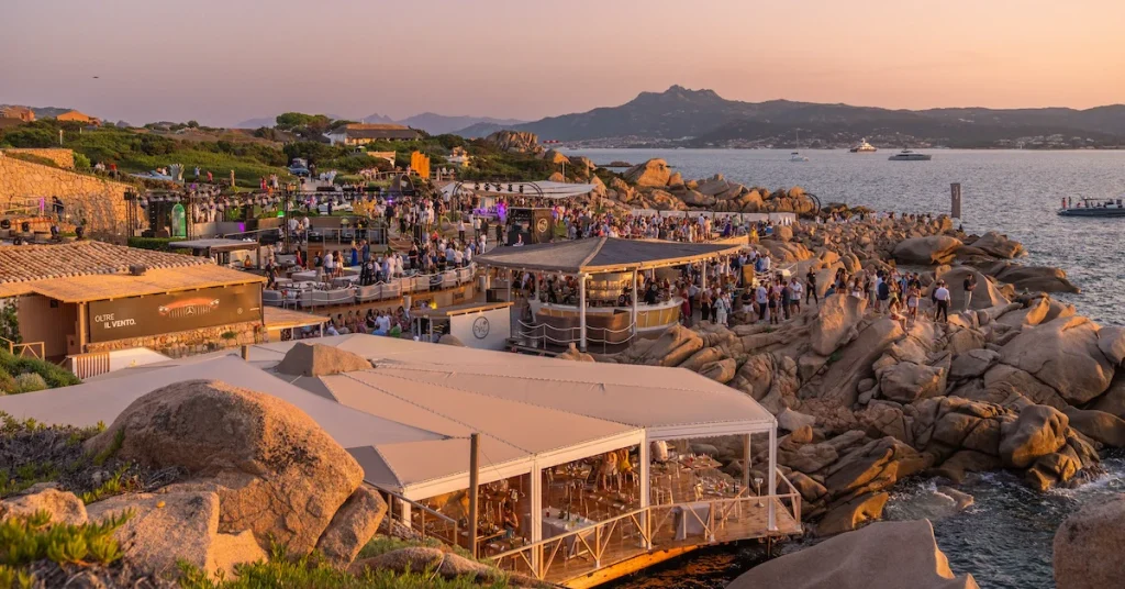 Aerial sunset view of a bustling beach club perched on rocks by the sea -luxury beach clubs in Europe