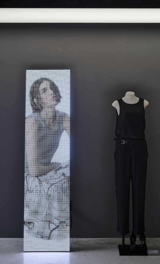 Gallery display pairing a digital screen portrait with a black sleeveless jumpsuit on a mannequin -top showrooms in São Paulo
