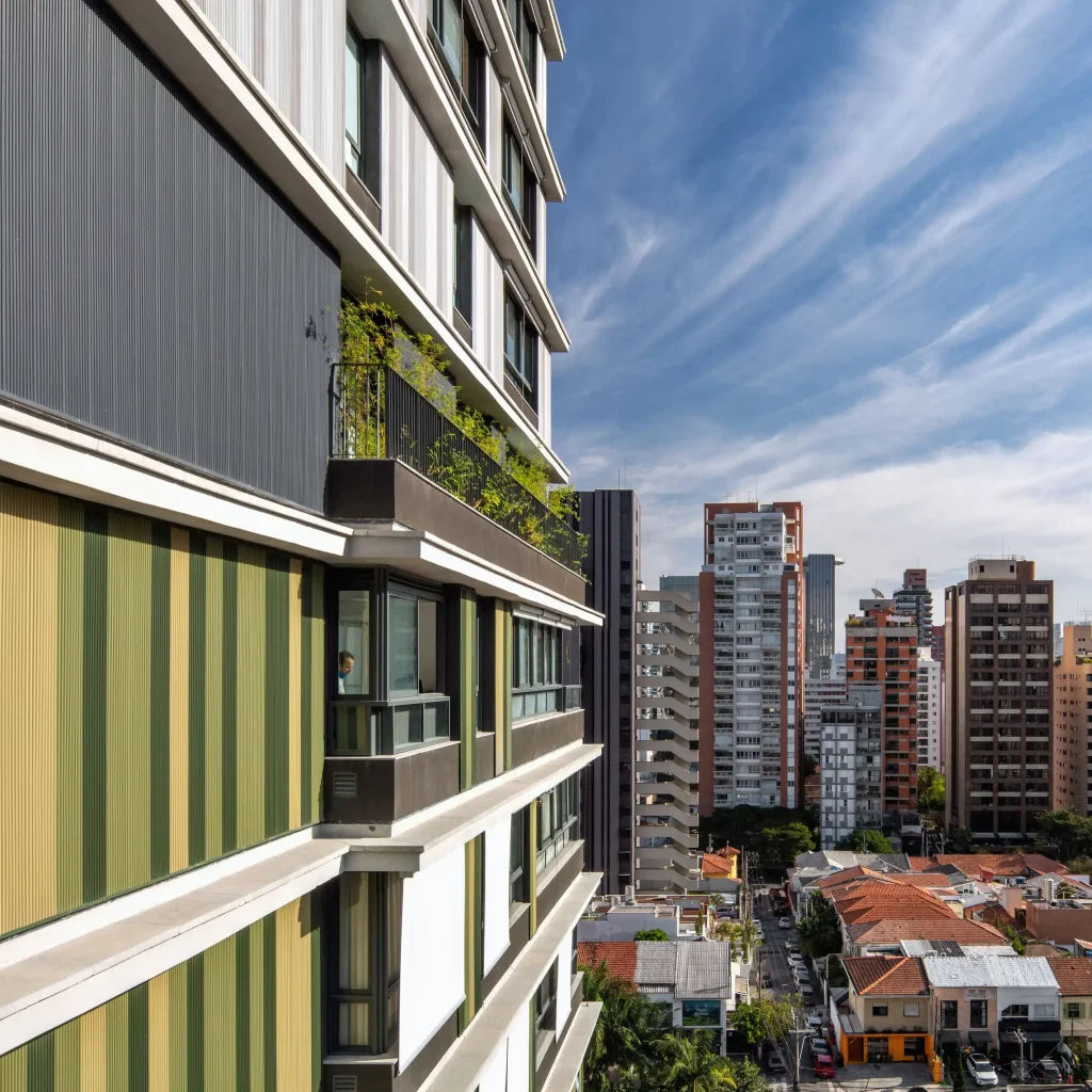 Side view of a modern building facade with green and yellow balconies, overlooking neighboring skyscrapers -top places to live in São Paulo