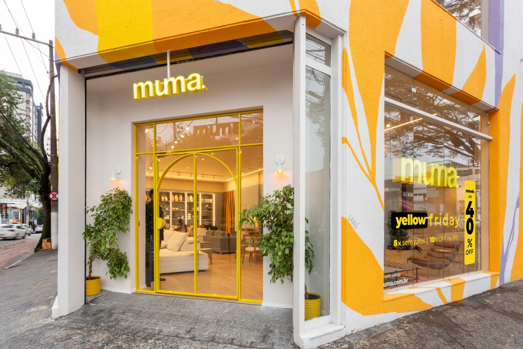 Muma storefront entrance with yellow-framed glass doors and a colorful mural facade -top showrooms in São Paulo