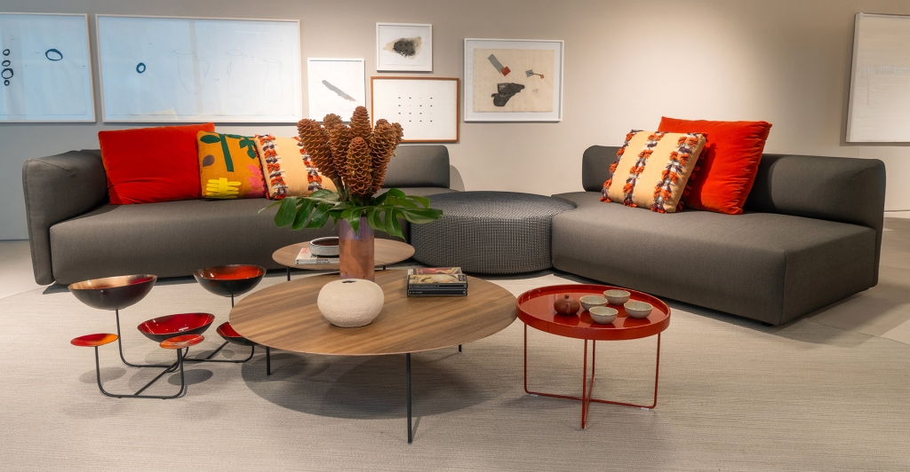 Living room seating area with grey sofas, colorful patterned cushions, and mixed round coffee tables -top showrooms in São Paulo
