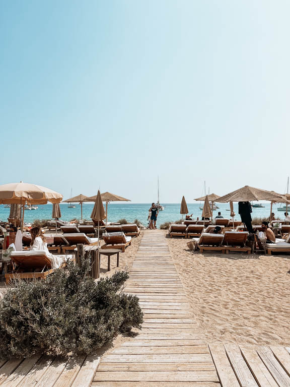 Wooden boardwalk between sun loungers and straw umbrellas by the sea -luxury beach clubs in Europe