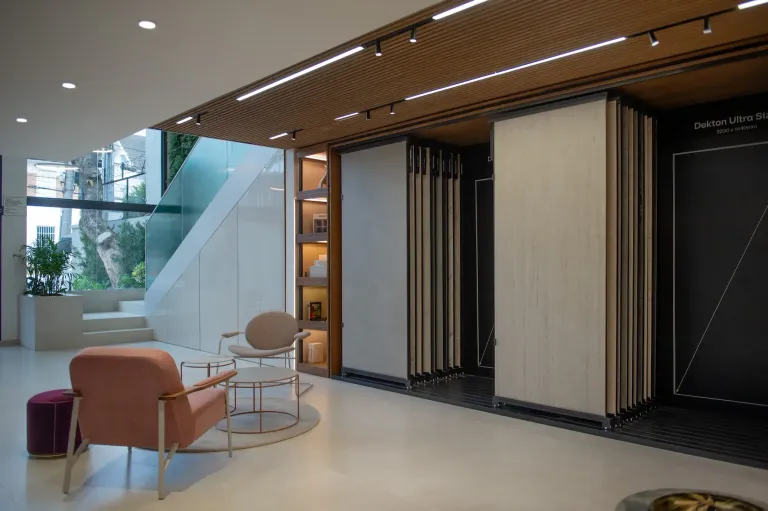 Cosentino showroom display wall with sliding stone slab samples beside pink and beige lounge chairs -top showrooms in São Paulo