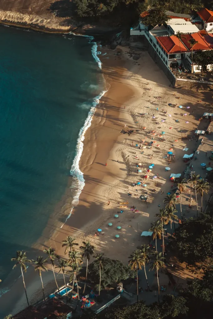 Aerial view of a sandy beach with umbrellas and palm trees in Rio de Janeiro -the best places to live in brazil