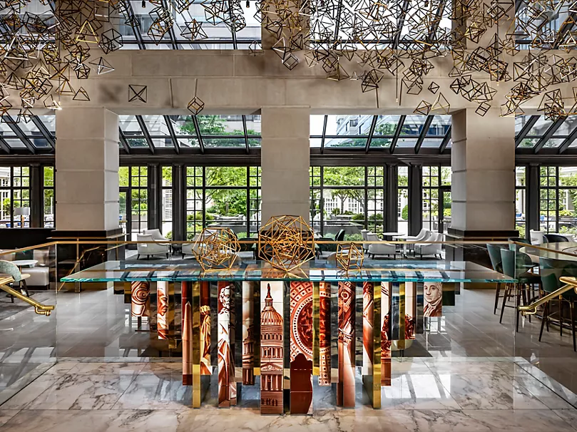 Wide-angle view of the hotel lobby featuring structured pillars, comfortable seating arrangements, and decorative patterned rugs - Fairmont Hotel.