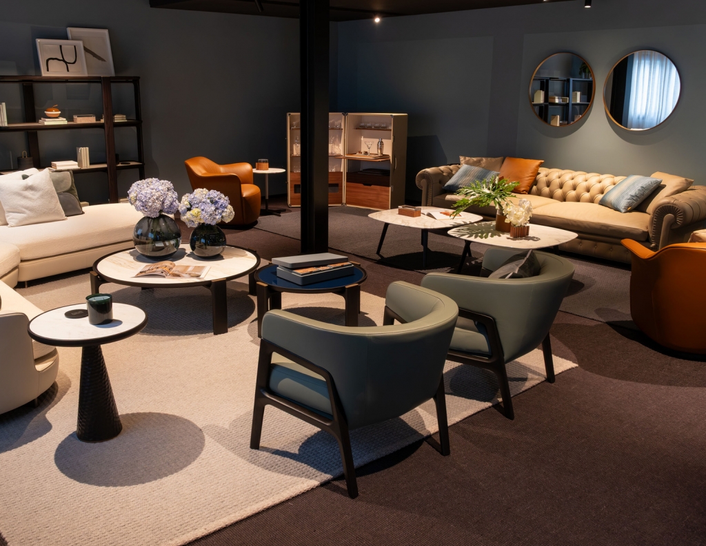 Showroom lounge with cream and camel sofas, green armchairs, marble side tables, and an open drinks cabinet -top showrooms in São Paulo