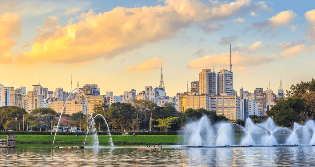 Water fountains in an urban lake with the city skyline and golden clouds at sunset -top places to live in São Paulo