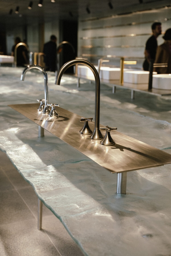 Showroom display of luxury bathroom faucets in chrome and brushed brass finishes mounted on a textured glass and stone counter -showrooms in Brazil