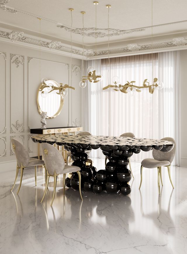 Rectangular table with stacked black sphere base beneath gold beaded branch chandeliers -luxury dining table