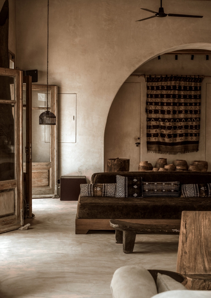 Rustic yet sophisticated interior with a stucco arch, ethnic textiles, and a velvet sofa -luxury beach clubs in Europe