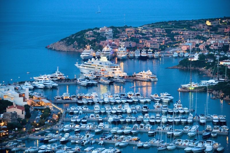 Yacht Destinations — luxury yachts moored in Porto Cervo Marina, surrounded by the stunning coastline of Sardinia, Italy