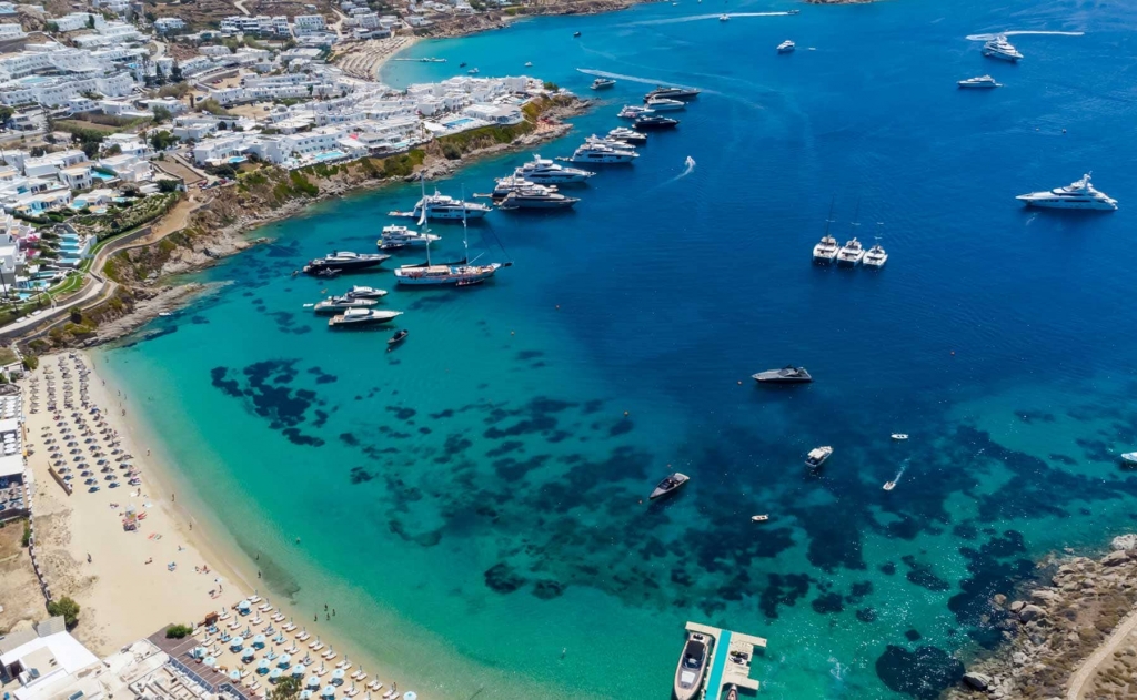Yacht Destinations — luxury yachts sailing along the stunning coastline of Mykonos, Greece, across the turquoise Aegean Sea