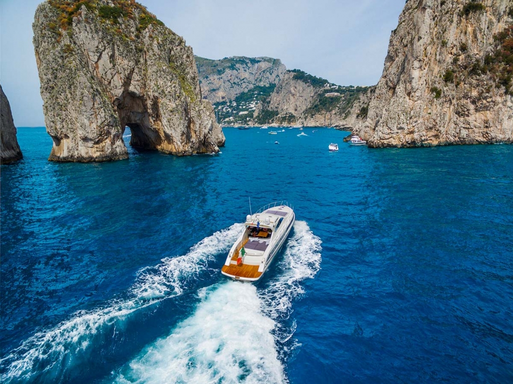 Yacht Destinations — luxury yacht sailing through the Mediterranean Sea surrounded by the dramatic rock formations of Capri, Italy