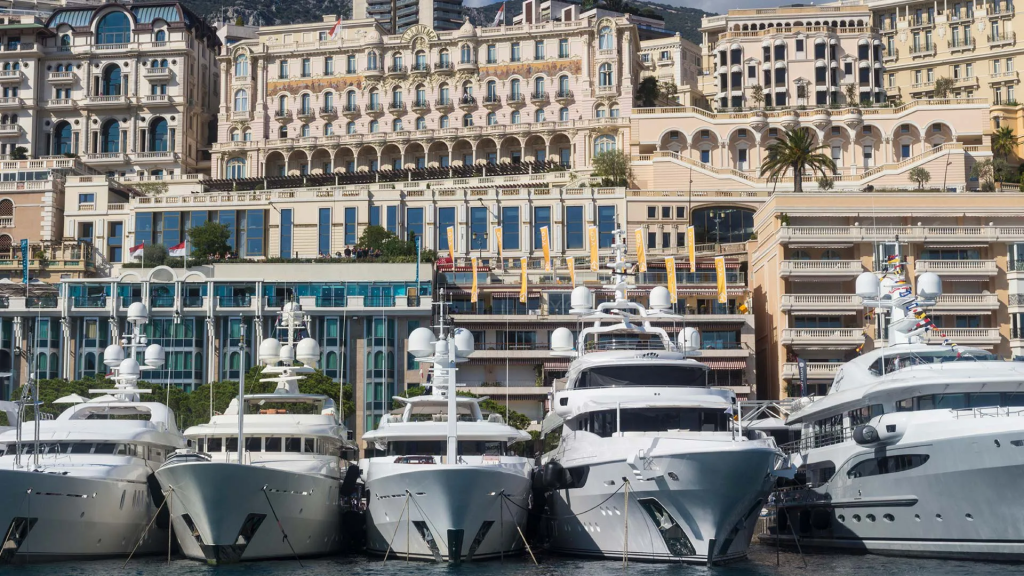 Yacht Destinations — luxury yachts moored in Monaco Marina with the city of Monaco rising behind them on the French Riviera