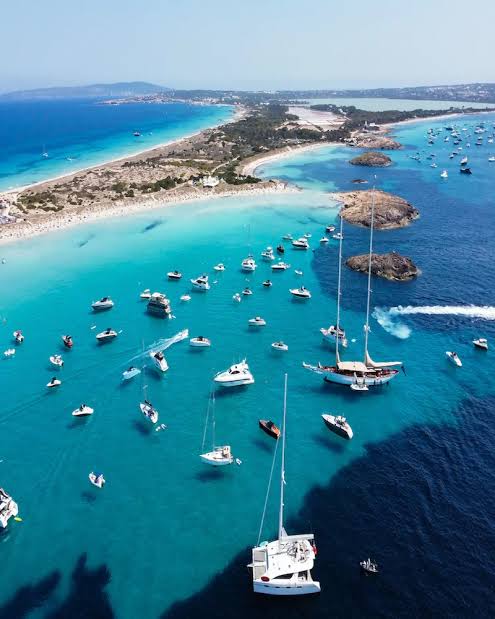 Yacht Destinations — aerial view of luxury yachts anchored in the crystal-clear turquoise waters of Formentera, Spain